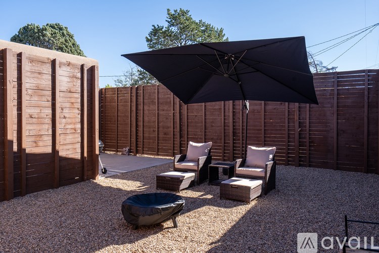 A patio with a black umbrella, white cushions, and a black bean bag chair.