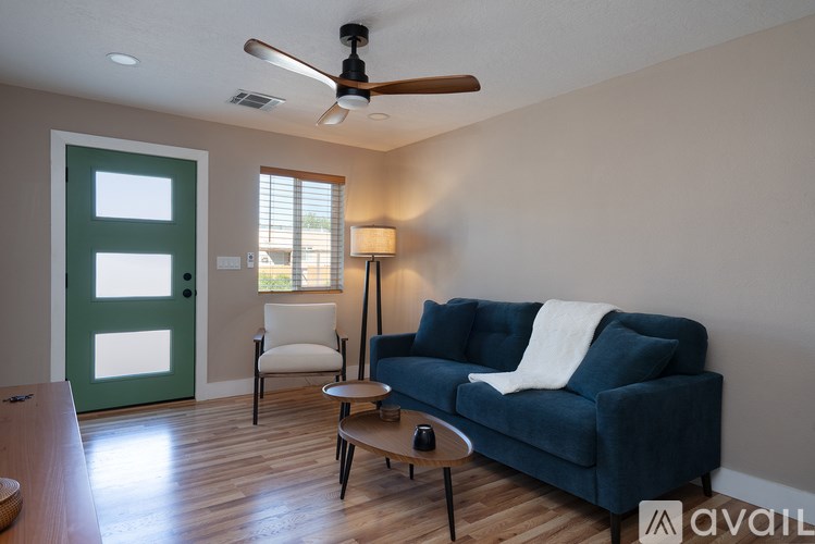 A living room with a blue couch and a green door.