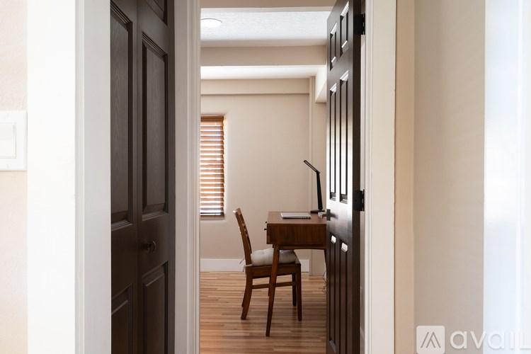 A wooden chair is placed in front of a desk with a lamp on it.