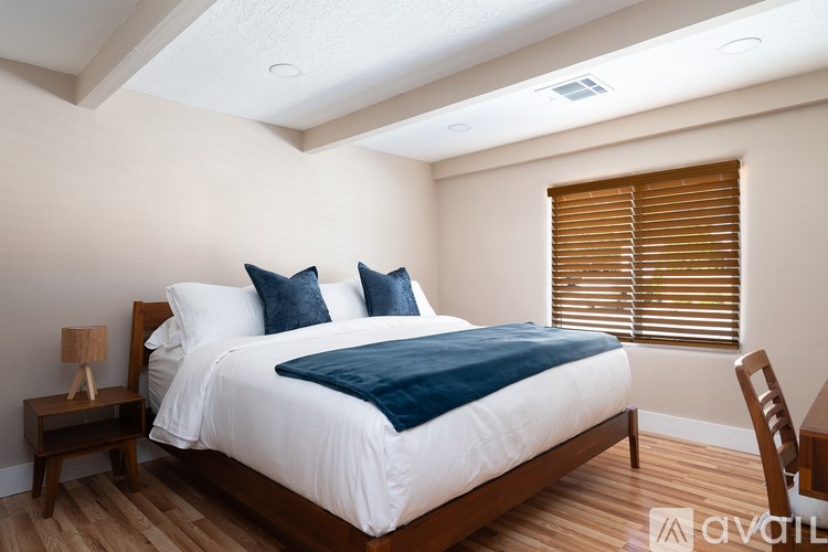 A bedroom with a bed, nightstand, and chair.