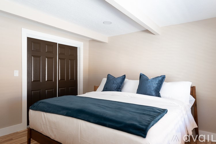 A bedroom with a bed, pillows, and a blue blanket.