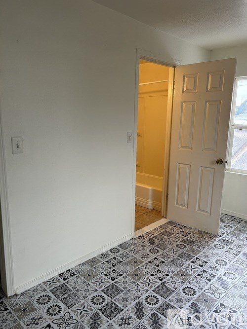 A room with a white door and a tiled floor.