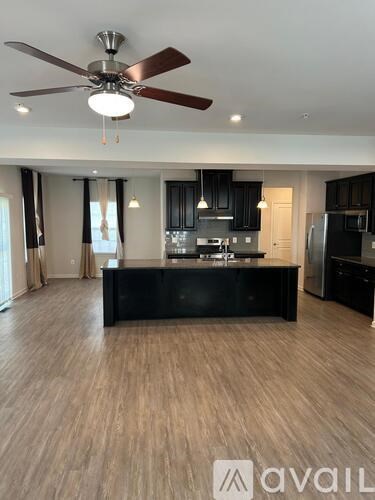 A spacious kitchen with a black island and wooden flooring.