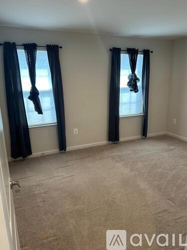 A room with two windows covered by black curtains.