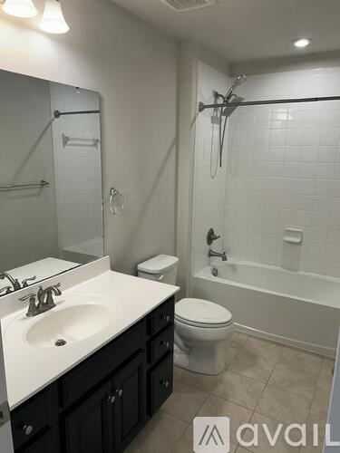 A bathroom with a white sink, black cabinets, and a white toilet.