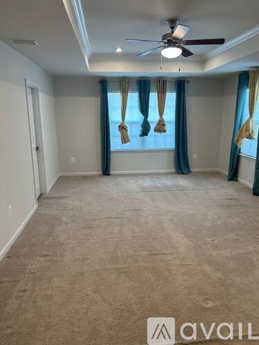 A spacious room with a ceiling fan and carpeted floor.