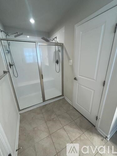 A bathroom with a glass shower door and a white door.