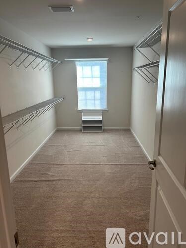 A long hallway with a window and shelves on the side.