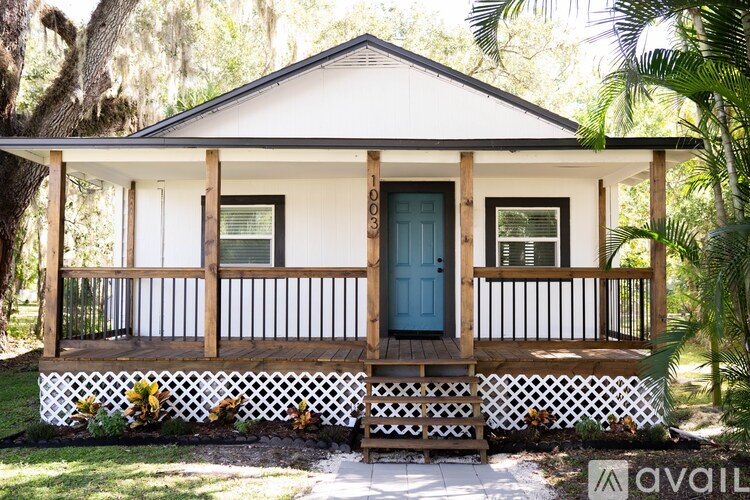 A small white house with a blue door and a porch.