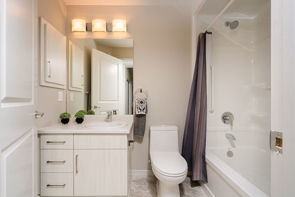 A white bathroom with a toilet, sink, and a shower.