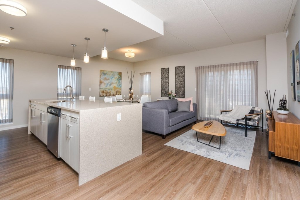 A modern kitchen with a wooden floor and a grey sofa.
