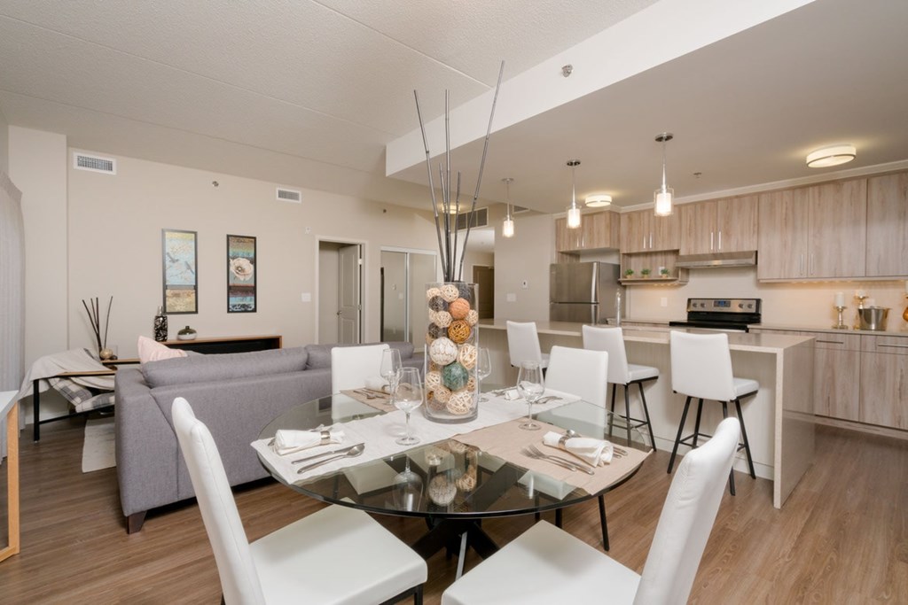 A modern dining room with a glass table and white chairs.