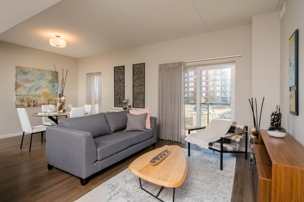 A grey couch sits in a living room with a wooden coffee table in front of it.