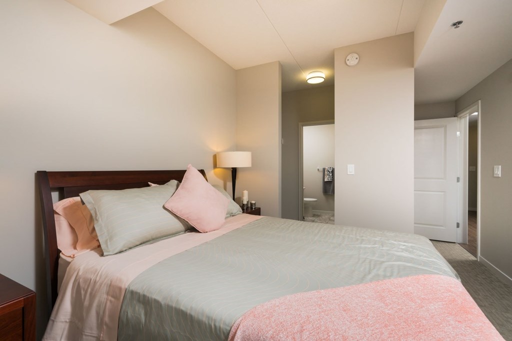 A bedroom with a bed, nightstand, and lamp.