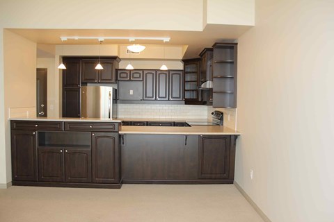 A kitchen with dark wood cabinets and a stainless steel refrigerator.