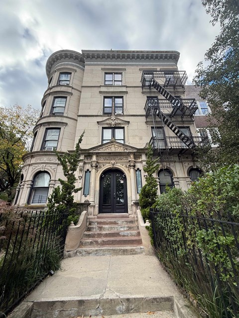 A large, old building with a black door and a fire escape on the side.