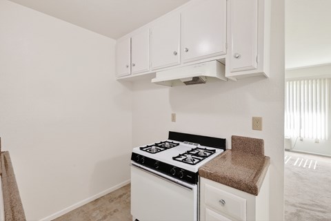 A white kitchen with a stove top oven and cabinets.