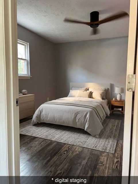 A bedroom with a bed, nightstand, and a ceiling fan.