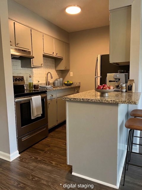 A kitchen with a white island and brown bar stool.