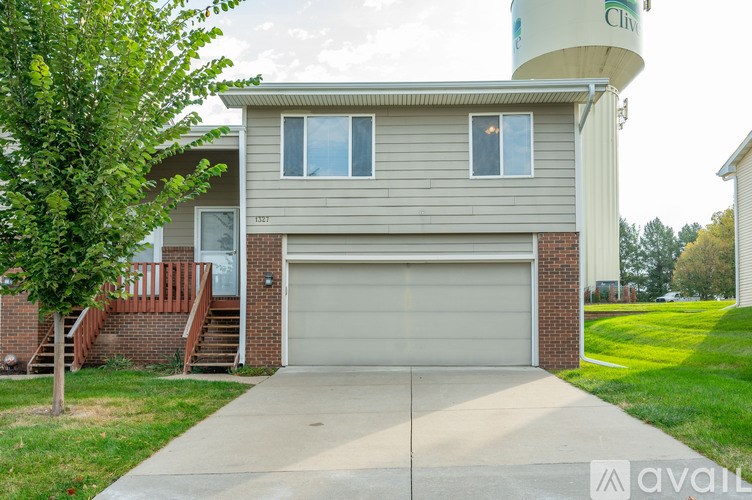A house with a garage and a tree in front.