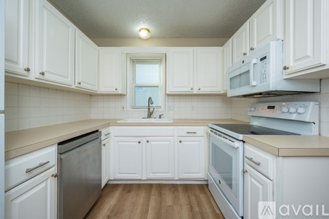 A kitchen with white cabinets and appliances.