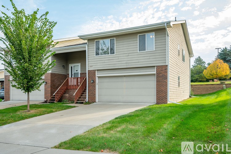 A house with a garage and a tree in front.