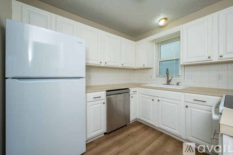 A white refrigerator is in a kitchen with white cabinets.