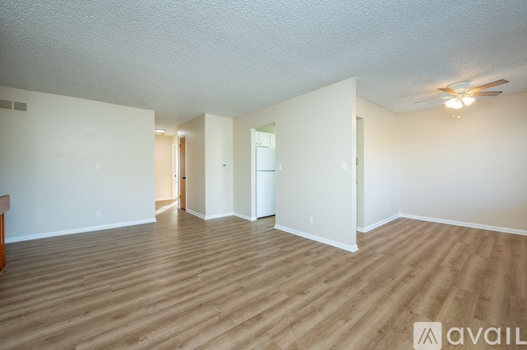 A spacious room with wooden flooring and white walls.
