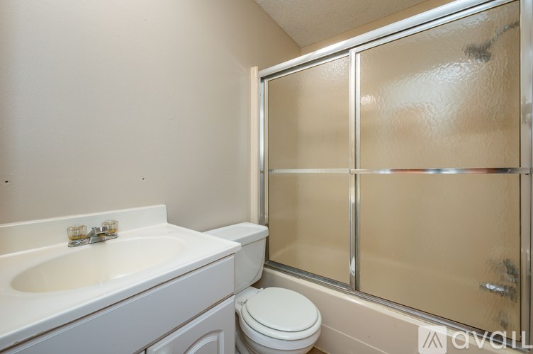 A white sink and toilet in a bathroom with a glass shower door.