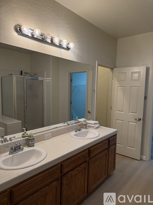 A bathroom with a double sink vanity and a mirror with lights above it.