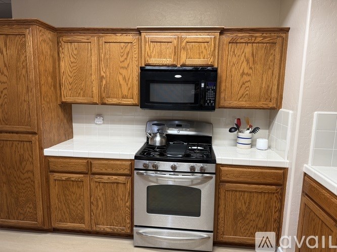A kitchen with wooden cabinets and a black microwave above the stove.