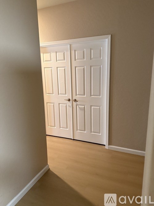 A white double door in a room with wooden flooring.