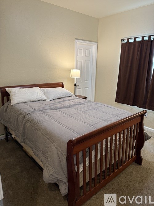 A bed with a wooden frame and a grey comforter is in the image.