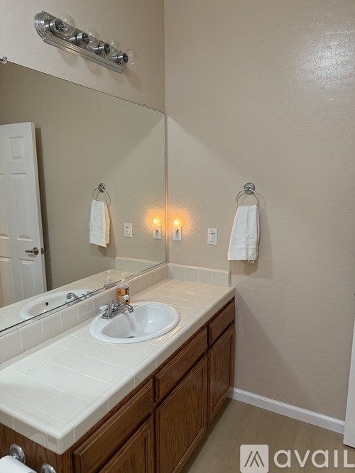 A bathroom with a sink, mirror, and towel rack.