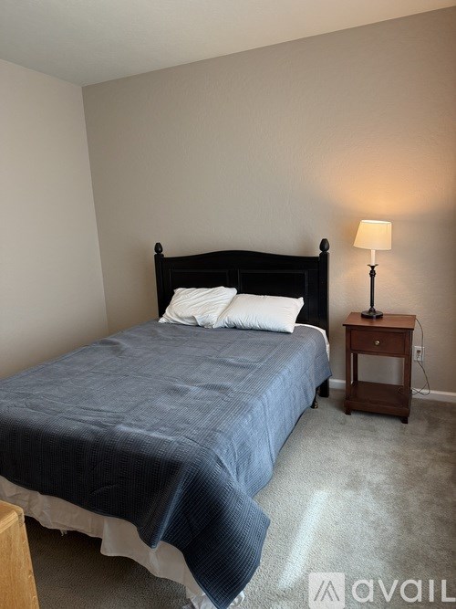 A bedroom with a bed, nightstand, and lamp.