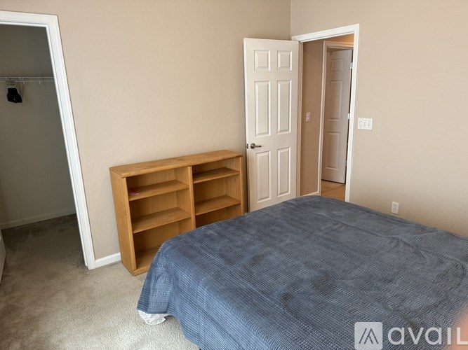A bedroom with a bed, dresser, and a wooden shelf.