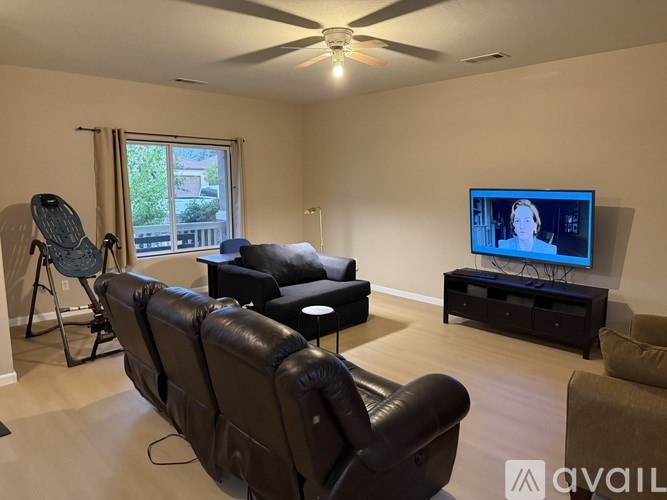 A living room with a brown leather couch and a television on a black stand.