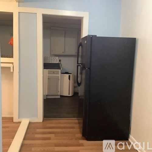 A black fridge in a kitchen with a white dishwasher and a white oven.
