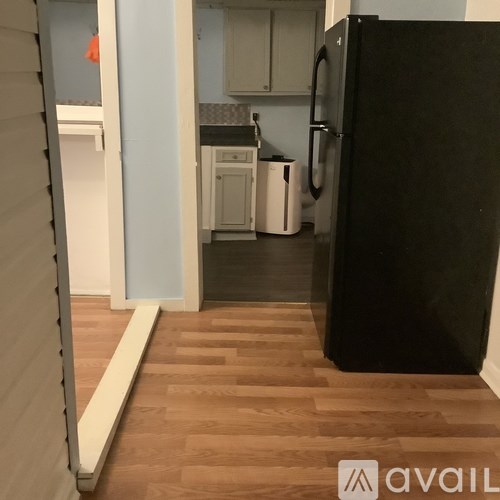 A kitchen with a black fridge and wooden floors.