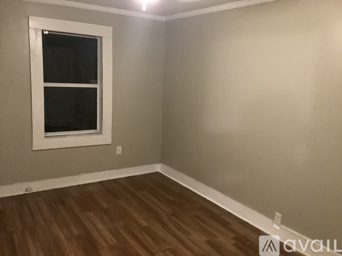 A room with a window and wooden flooring.