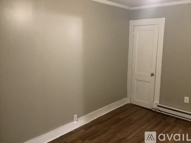A room with a white door and wooden floor.