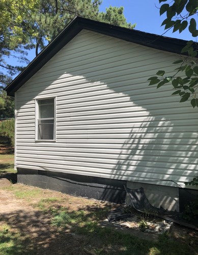 A small house with a window and a black roof.