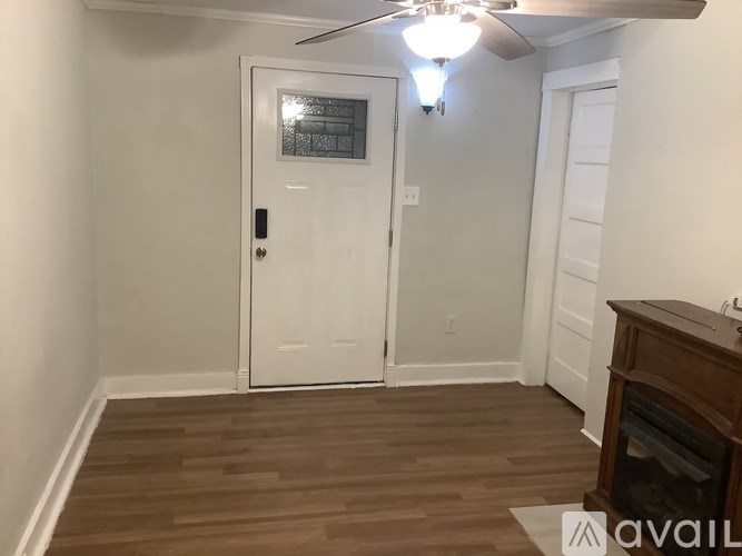 A room with a white door and a ceiling fan.