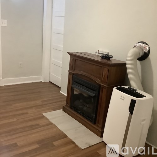 A wood stove is in a corner of a room with a wall-mounted air purifier.