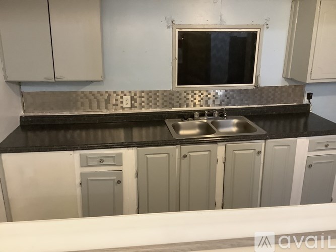 A kitchen with a black countertop and white cabinets.