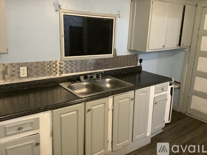 A kitchen with white cabinets and a black countertop.
