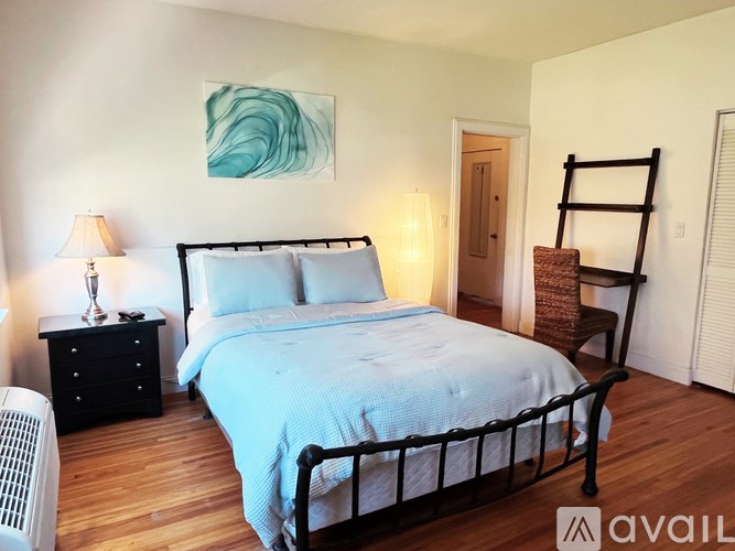 A bedroom with a bed, nightstand, and chair.