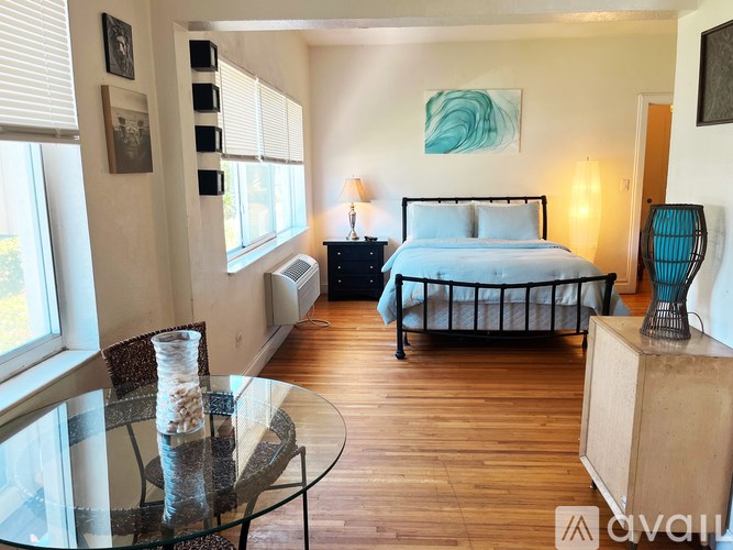 A bedroom with a bed, nightstand, and a table with a vase on it.