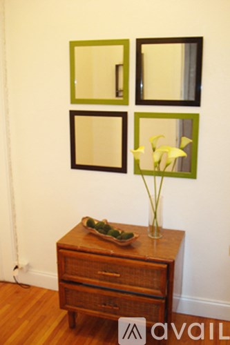 A wooden chest of drawers with a vase of flowers on top.