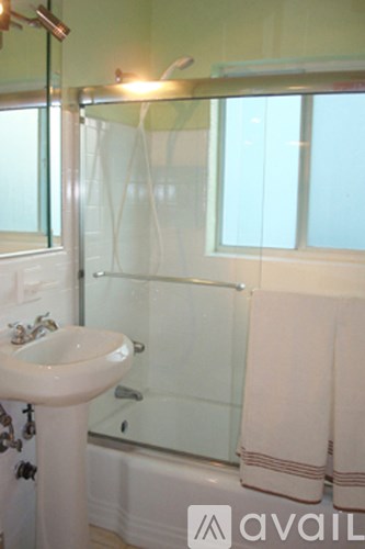A bathroom with a sink, mirror, and shower.